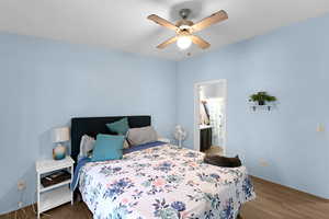 Bedroom with ensuite bathroom, dark wood-type flooring, and ceiling fan