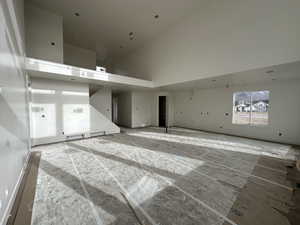 Unfurnished living room featuring a towering ceiling