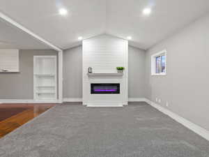 Living room with hardwood / wood-style floors, a fireplace, built in features, and lofted ceiling