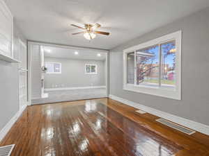 Unfurnished living room featuring a textured ceiling, dark hardwood / wood-style flooring, and ceiling fan