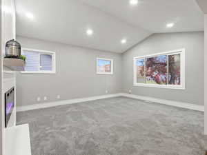 Unfurnished living room with lofted ceiling and carpet