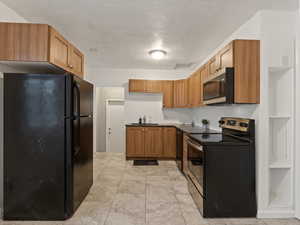 Kitchen with a textured ceiling, black appliances, and sink