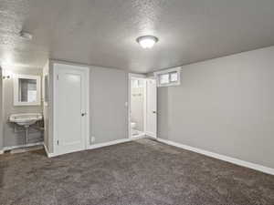 Unfurnished bedroom featuring a textured ceiling, carpet floors, and ensuite bath