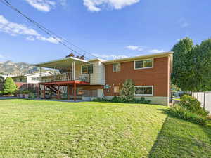 Rear view of house with a deck with mountain view, a lawn, and a patio