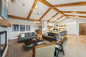 Living room featuring light hardwood / wood-style floors, a chandelier, sink, and vaulted ceiling with beams