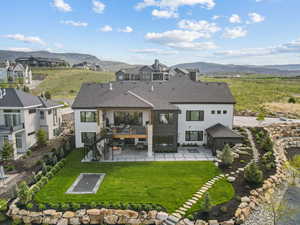 Back of property with a patio, a mountain view, a yard, and a shingled roof