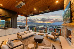 Patio terrace at dusk featuring an outdoor kitchen, a mountain view, a grill, and an outdoor living space with a fireplace