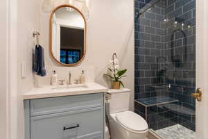 Bathroom with vanity, toilet, and tiled shower