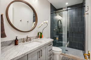 Bathroom with tile patterned floors, vanity, toilet, and an enclosed shower