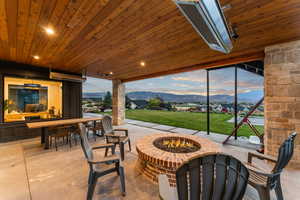 Patio terrace at dusk with a yard, a fire pit, and a mountain view