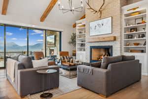 Living room featuring beam ceiling, a mountain view, a large fireplace, and light hardwood / wood-style flooring