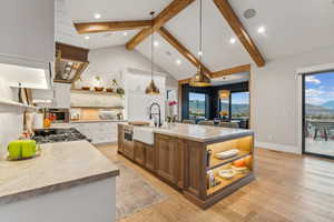 Kitchen with hanging light fixtures, white cabinetry, sink, and light hardwood / wood-style flooring