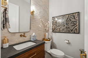 Bathroom featuring toilet, backsplash, and vanity