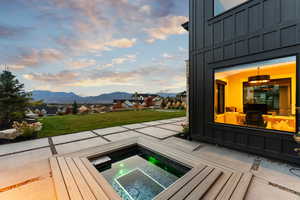 Patio terrace at dusk featuring a mountain view, an in ground hot tub, and a yard