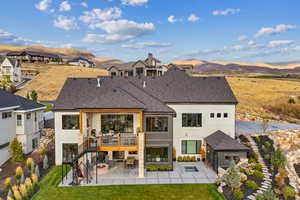 Rear view of property with a mountain view, an outdoor fire pit, a yard, and a patio area