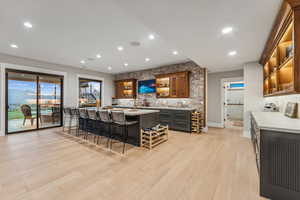 Kitchen with a center island with sink, light wood-type flooring, backsplash, and a breakfast bar