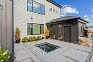 Back of house featuring a patio and an outdoor hot tub