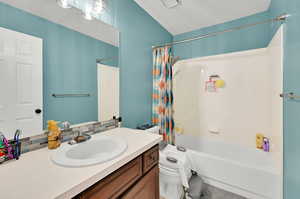 Full bathroom featuring toilet, vanity, shower / bath combination with curtain, and decorative backsplash