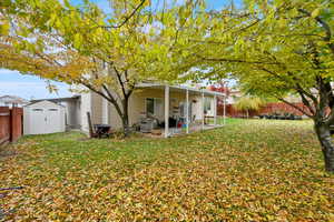 Back of house with a patio, a yard, and a shed