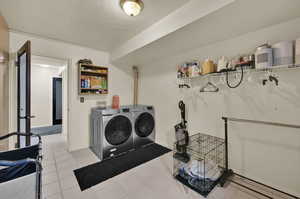 Laundry area with washing machine and dryer, a textured ceiling, light tile patterned floors, and a baseboard heating unit