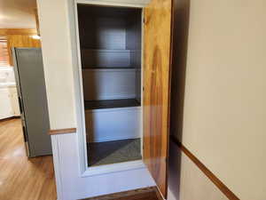 Room details with wood walls, hardwood / wood-style flooring, and stainless steel refrigerator