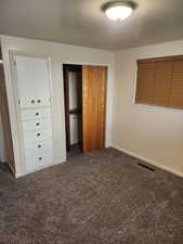 Unfurnished bedroom with a closet and dark colored carpet