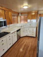 Kitchen with white cabinets, sink, light hardwood / wood-style flooring, and appliances with stainless steel finishes