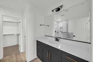 Bathroom featuring hardwood / wood-style flooring, vanity, and tiled shower