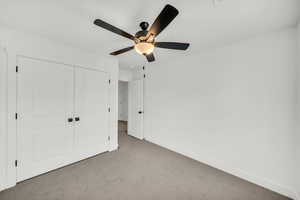 Unfurnished bedroom featuring ceiling fan, a closet, and light colored carpet