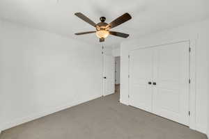 Unfurnished bedroom featuring ceiling fan, light carpet, and a closet