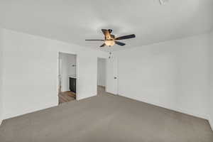 Unfurnished bedroom featuring light colored carpet, ceiling fan, and ensuite bathroom