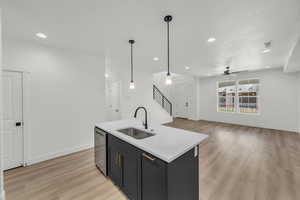 Kitchen with hanging light fixtures, light hardwood / wood-style floors, sink, and dishwasher