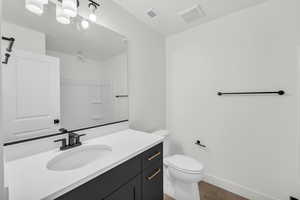 Bathroom featuring toilet, vanity, and hardwood / wood-style floors