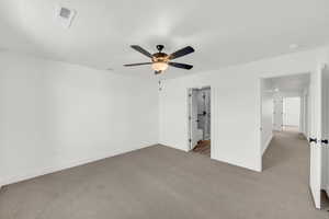 Unfurnished bedroom with ceiling fan, connected bathroom, and light colored carpet