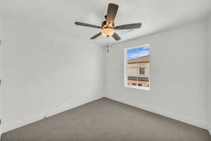 Carpeted spare room with ceiling fan