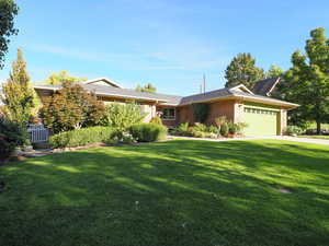 Single story home with a garage and a front lawn