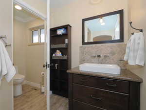 Bathroom with toilet, hardwood / wood-style floors, vanity, and crown molding