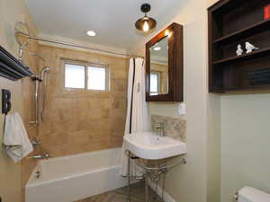 Bathroom with toilet and shower / bathtub combination with curtain