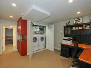 Clothes washing area featuring washing machine and clothes dryer, a textured ceiling, and light carpet