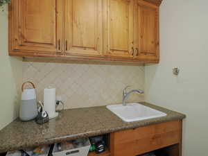 Kitchen featuring dark stone countertops, tasteful backsplash, and sink