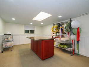 Kitchen with light colored carpet, a textured ceiling, and a center island