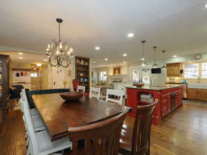 Dining room featuring dark wood-type flooring, a fireplace, sink, and an inviting chandelier