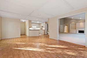 Unfurnished living room with lofted ceiling, light parquet flooring, and crown molding