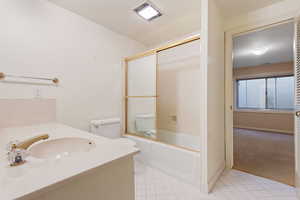 Full bathroom with enclosed tub / shower combo, vanity, and toilet