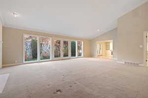 Carpeted spare room with high vaulted ceiling and ornamental molding