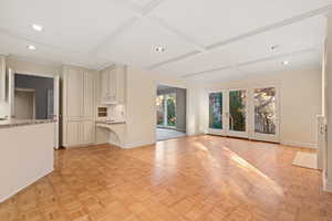 Unfurnished living room featuring light parquet floors, coffered ceiling, and crown molding