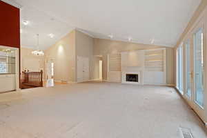 Unfurnished living room with high vaulted ceiling, light carpet, and crown molding