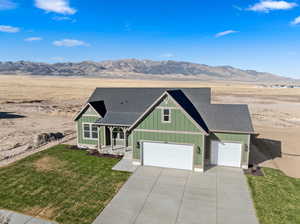 View of front of home featuring a front lawn, a mountain view, and a garage