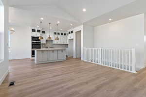 Kitchen with an island with double ovens, wood hood, and designer finishes
