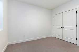 Unfurnished bedroom featuring light carpet and a closet